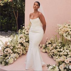 a woman standing in front of flowers wearing a wedding dress