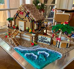 a gingerbread house is decorated with icing and palm trees, beach decorations, and surfboards