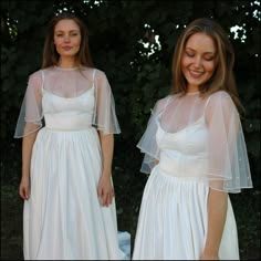 two women in white dresses standing next to each other with veils over their shoulders