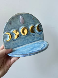 a hand holding a blue and gold plate with phases on it