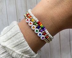 a woman's arm with several bracelets on it, including beads and hearts