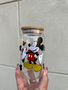 a person holding up a glass with a mickey mouse design on the inside and bottom