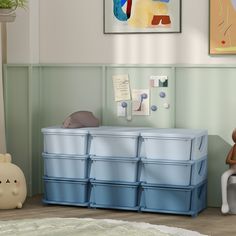 a baby's room with blue storage bins and a teddy bear on the floor