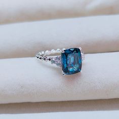 a blue stone ring sitting on top of a white cloth