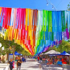 people are walking under colorful streamers hanging from the ceiling