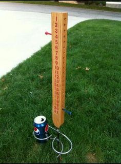 a wooden sign sitting in the grass next to a paint can and a sprayer