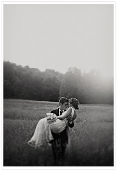 black and white photo of bride and groom kissing in field