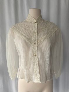 "Sweet cute 1950's women's white sheer button-down pintucked blouse with lace decoration, puffy bishop sleeves and sparkly buttons by Sir James Made in California Good vintage condition with small snags on back and stain on front and 2nd & 3rd button have lost their sparkles No size tag Measurements (laying flat): Pit to Pit: 17 1/2\" Back Length w/o Collar: 1/ 1/2\" Our items are vintage, older and/or pre-loved and may show signs of age. Items may have some imperfections, including small holes, Spring Wedding Button-up Blouse, Classic Sheer Button-up Blouse, Classic Sheer Blouse For Fall, Vintage Lace Collar Button-up Top, Formal Lace Top Button-up Blouse, Formal Lace Blouse With Button Closure, Cream Tops For Fall Wedding, Cream Tops For Wedding In Fall, Vintage Puff Sleeve Blouse With Buttons