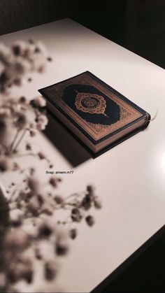 a book sitting on top of a white table next to a vase filled with flowers