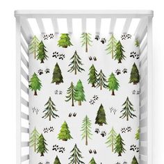 a white crib with green trees and paw prints on the bottom, and an animal print