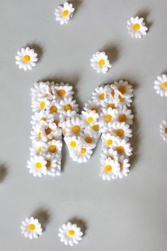 the word mom spelled with daisies on a white surface