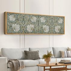 a living room with a white couch and wooden coffee table in front of a painting on the wall