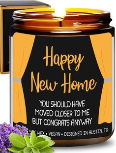 happy new home jar candle with purple flowers and green leaves next to it on a white background