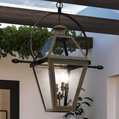 an outdoor light hanging from the ceiling next to a potted plant