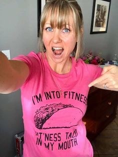 a woman in a pink shirt pointing at the camera