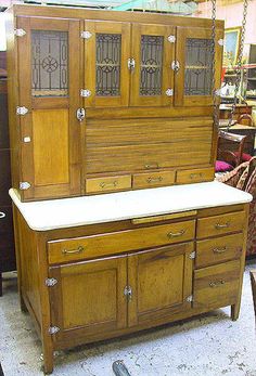 an old wooden cabinet sitting on top of a floor next to a table and chairs