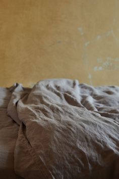 an unmade bed with brown sheets and pillows