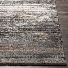 an area rug with various colors and patterns on the floor, including greys, browns, and beiges