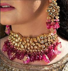 a close up of a woman's necklace and earring with pink stones on it