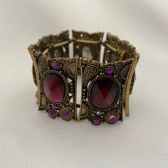 "This vintage brass and amethyst glass bracelet has an oriental flair. It consists of 7 elements strung together by strong rubber stretch bands. It is expandable.  Dimensions Approx. 2.36\" (6 cm) diameter x 1.57\" (4 cm) H. The width of each individual element is approx. 2\" (5 cm). The bracelet is in very good used condition." Vintage Purple Jewelry For Festival, Adjustable Vintage Purple Jewelry, Vintage Adjustable Purple Jewelry, Vintage Purple Bangle Jewelry, Bohemian Metal Bracelets With Antique Finish, Bohemian Metal Bracelet With Antique Finish, Adjustable Bohemian Bracelet With Antique Finish, Bohemian Antique Gold Adjustable Bracelets, Adjustable Metal Bohemian Stretch Bracelet