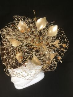 Delicate gold fascinator perfect for the guest who wants something fairly understated. This design is a beautiful selection of glass effect leaves and flowers with an additional scatter of brown crystal and tan glacier stone, clustered together amongst a fine layer of veiling and set onto a fine comfort base tiara band. As with all our designs, this piece can be made exact to the image or in any colour combination to match in with your outfit. If a specific colour is required customers can messa Handmade Gold Hat For Kentucky Derby, Elegant Headpiece With Handmade Flowers, Elegant Headpieces With Handmade Flowers As Gift, Elegant Handmade Headpiece With Structured Crown, Handmade Gold Headpiece With Pinched Crown, Beige Structured Crown Fascinator For Party, Elegant Headpieces With Handmade Flowers For Events, Elegant Handmade Flowers Headpiece For Events, Elegant Handmade Mini Hats For Wedding