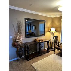 a living room filled with furniture and a large mirror on top of a dresser next to a lamp