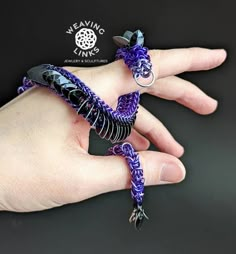 a woman's hand holding two purple and black bracelets