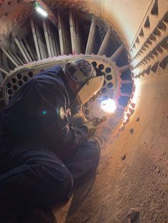 a man working in a tunnel using a torch to light up the holes on the wall