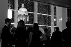 people are standing in front of a window with lights on it and the capitol building behind them