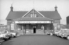 an old black and white photo of a building with cars parked in front of it