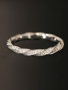 a white gold wedding ring with diamonds on it's sides and an intricate twist in the middle