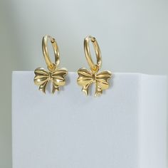 we have entered our bow era 🎀 update your style with our Wrap Me Up Huggie Hoop Earrings. this trendy accessory features the latest bow craze in the fashion industry, adding a touch of femininity and sparkle to your look. explore your delicate side with our collection of bow necklaces and earrings. the perfect addition to any outfit. 18k gold pvd over stainless steel bows measures 12x7.5mm huggies are 3x10.5mm round since we love versatility, bow charms are removable and huggies can be worn alo Girly Christmas Gifts, Girly Christmas, Brazilian Gold, Synthetic Diamond, Gold Bond, Bow Necklace, Christmas Inspo, The Fashion Industry, Huggie Hoop Earrings