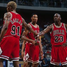 three basketball players are standing together in the middle of a court with their hands on each other's shoulders