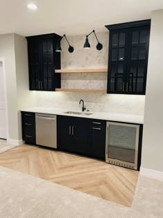 an empty kitchen with black cabinets and stainless steel appliances in the middle of the room