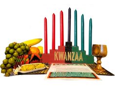 an assortment of candles, fruit and bread are arranged on a table with the words kwanza written in front of them