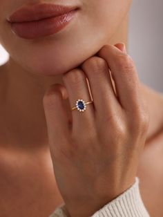 a close up of a person wearing a ring with a blue stone on the middle