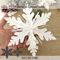 the paper snowflake is being held by someone's hand