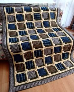 a couch with a quilt on top of it next to a wooden floor and window