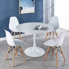 a white table with four chairs and a magazine on the top of it in front of a blue wall