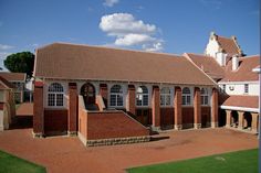 an old brick building with a clock tower in the background and green grass around it