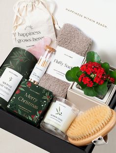 an open gift box containing candles, soaps and other items for the holiday season