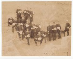 an old photograph of men in ski gear posing for a group photo on the side of a mountain