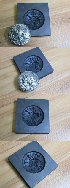 three metal plates sitting on top of a wooden table next to two black coasters