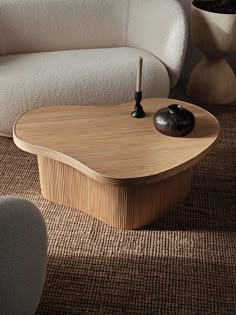 a wooden table sitting on top of a rug next to a white chair and vase