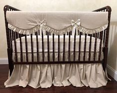 a baby crib with white ruffles and bows on the bed skirting