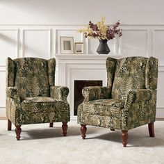 two leopard print chairs in front of a fire place with a vase on the mantel