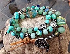 Triple Wrap OM Bracelet ~~ hand-knotted rolled leather with turquoise, jade, silver and Czech glass beads. Finishes with a OM button and suede loop. Triple wrap (shown)-$105/ Double wrap-$80 Mermaid Tears Jewelry is hand-created and inspired by the sea. I use the finest supplies including Thailand Hill Tribe Silver, Swarovski crystal, Czech glass beads, freshwater pearls, sterling silver wire and chain, authentic sea glass from all over the world and an array of semi-precious stones. Mermaid Tears Jewelry specializes in custom jewelry. Please let me know if you have a special request. I am happy to accommodate! Each piece of my jewelry is made to order. This way you can choose the length or color you like best. Like shells on the beach, no two pieces of jewelry are exactly alike.. MORE INF Hand Wrapped Turquoise Spiritual Wrap Bracelet, Spiritual Green Wrap Bracelet For Festival, Handmade Turquoise Wrap Bracelet, Turquoise Wrap Bracelet Great For Gifts, Turquoise Wrap Bracelet Gift, Spiritual Turquoise Hand Knotted Jewelry, Artisan Turquoise Hand Wrapped Wrap Bracelet, Artisan Hand Wrapped Turquoise Wrap Bracelet, Spiritual Hand-knotted Turquoise Jewelry