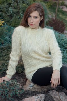 a woman sitting on the ground wearing a sweater