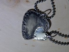 a metal heart shaped pendant on a ball chain