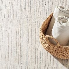 a basket with two cloths in it on top of a carpeted floor next to a pair of shoes